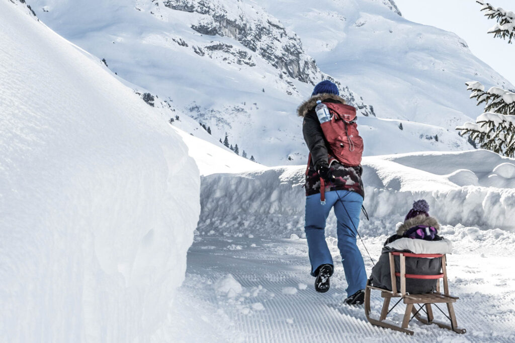 Frau zieht Kind am Rodel | Skiurlaub mit Kindern am Arlberg
